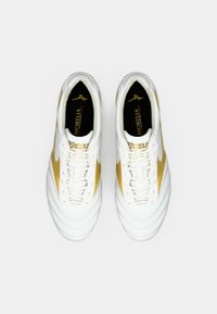 Nogometni kopački belo-zlate barve z gladkim usnjenim zgornjim delom, rebrasto teksturo na prstu ter logotipom znamke na jezičku in strani.