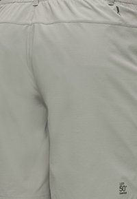 Shorts gris clair avec taille élastique, étiquette de protection solaire UPF 50+ SolarPack et petit logo noir près de la taille.