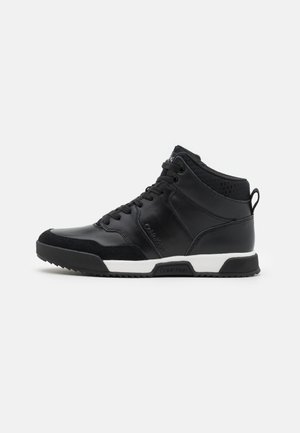 Czarny wysokoprofilowy sneaker z sznurowaniem z przodu, biała środkowa podeszwa, czarna teksturowana podeszwa zewnętrzna oraz materiałowa pętelka na pięcie.