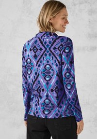 Langärmliges lila Hemd mit blauen und schwarzen geometrischen Mustern, das eine glatte Textur und ein tailliertes Design aufweist. Rückansicht gezeigt.