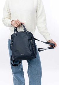 Zaino in nylon blu navy con doppi manici e spallacci regolabili, dotato di cerniere argentate e tasche anteriori per un accesso facile.