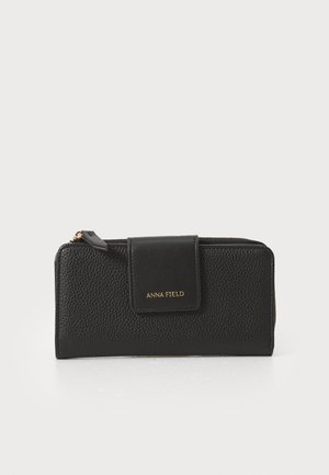 Black leather wallet with a textured finish, featuring a magnetic flap closure and gold lettering "ANNA FIELD" on the front.