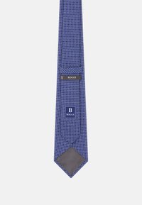 Sininen kuvioitu solmio, joka on valmistettu kudotusta kankaasta, jossa on geometraalinen muotoilu, terävä kärki ja etiketti, jossa lukee "BOGGI" ommeltuna taakse.