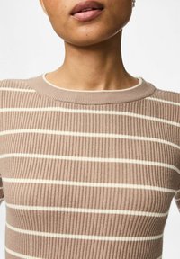 Ribbade stickade toppar i ljusbrunt med vita horisontella ränder. Har rund halsringning och textil med en figurnära design.
