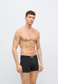 Crne bokserice s uzorkom dijamanta u kontrastnoj bijeloj boji. Elastični pojas s istaknutim natpisom robne marke "BOSS".