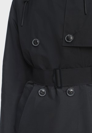 Černý voděodolný kabát s páskem v pase, velkými knoflíky a dvojitým zapínáním. Hladká textura, moderní střih a praktické detaily.