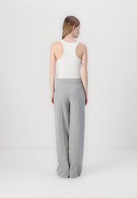White ribbed tank top with thick straps paired with loose, light gray sweatpants. Simple design with a soft texture, no visible patterns.