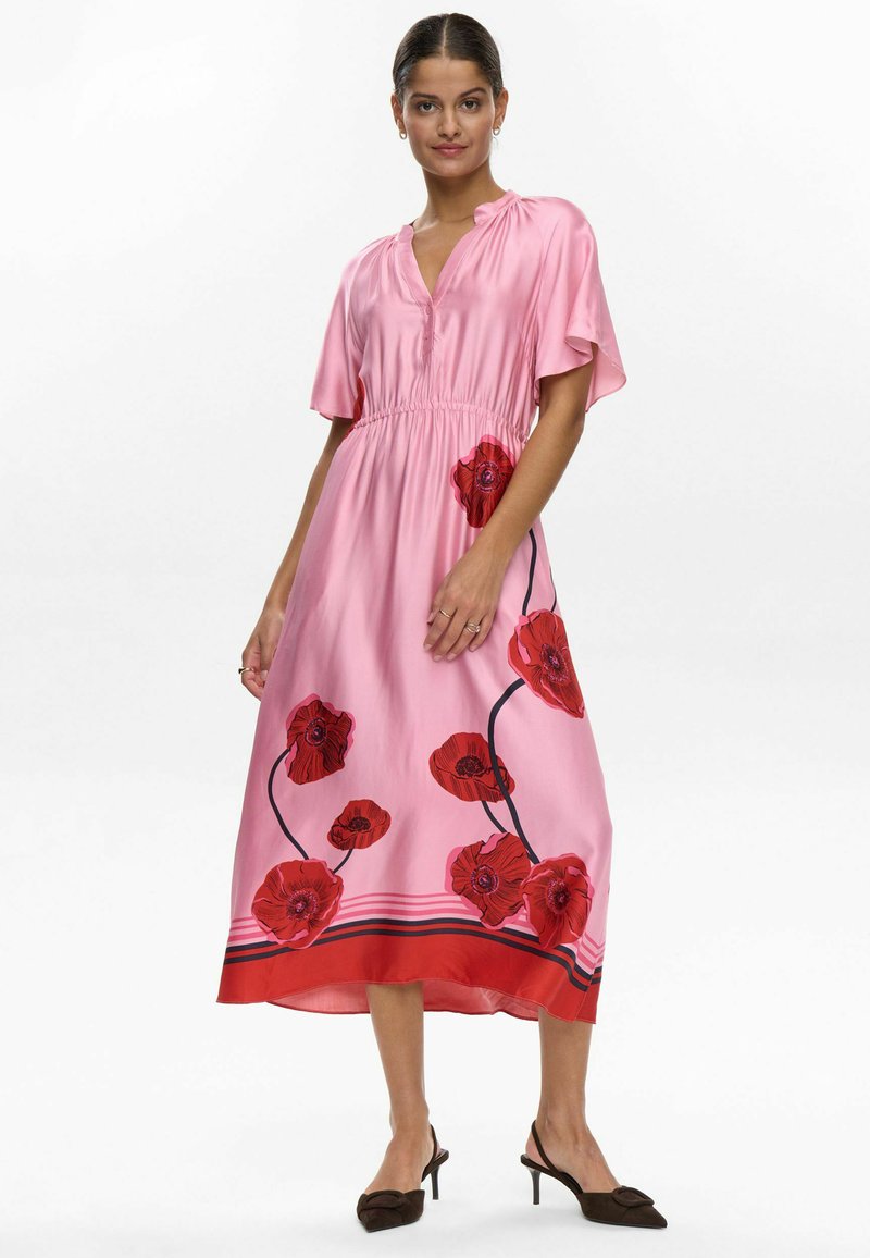 Pink dress made of satin material with short flutter sleeves, featuring large red floral patterns and a cinched waist, complementing the hem.