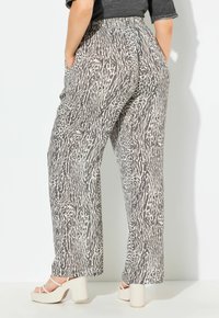 Wijde broek in een zwart-wit dierenprint, met een elastische tailleband en zijzakken, gecombineerd met chunky blockhak-sandalen.