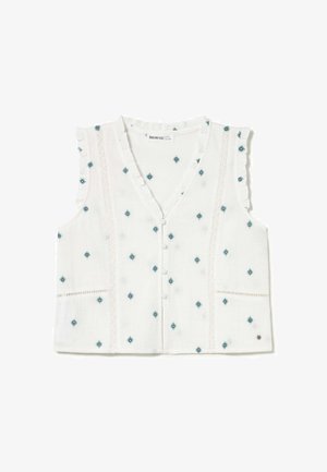 Blouse blanche sans manches avec motifs brodés bleus, boutonnage devant, bords froncés aux épaules et panneaux ornés de dentelle.