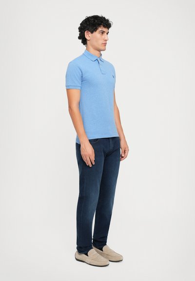 Lichtblauwe polo met korte mouwen, gemaakt van een zachte stof. Slim-fit ontwerp in combinatie met donkere jeans en beige instappers.