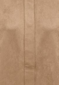 Lysebrunt imiteret ruskindstof med en glat tekstur og en central søm. Overfladen har en subtil glans og jævn farve.