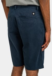 Shorts bleu marine en tissu doux, dotés d'une poche arrière, d'accents cousus et d'un patch logo sur la ceinture.