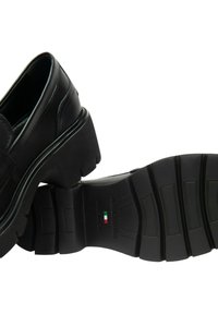 Mocassini neri con suola chunky, tredatura spessa, cuciture visibili e etichetta "Made in Italy" con bandiera italiana sulla suola.