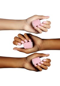 Tre mani mostrano una bottiglia di smalto per unghie di un rosa pallido. Ogni mano ha unghie ben curate nella stessa tonalità di rosa tenue.