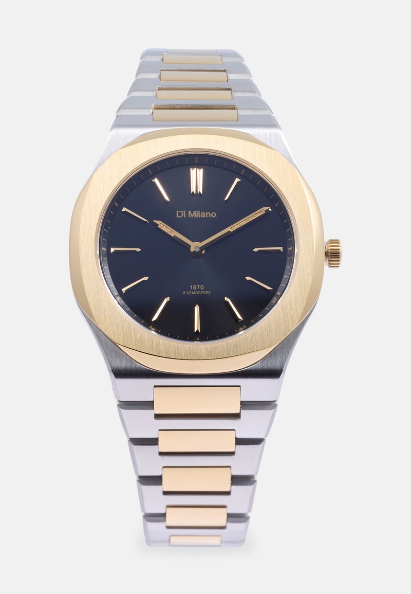 Relógio em aço inoxidável com mostrador em gradiente azul-marinho, detalhes em dourado e um bezel escovado em ouro. A pulseira de elos apresenta elos em ouro e prata alternados.