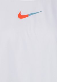 Camiseta atlética blanca con un logo de Nike rojo y azul en el pecho. Fabricada con un tejido suave y liso, de corte ajustado.