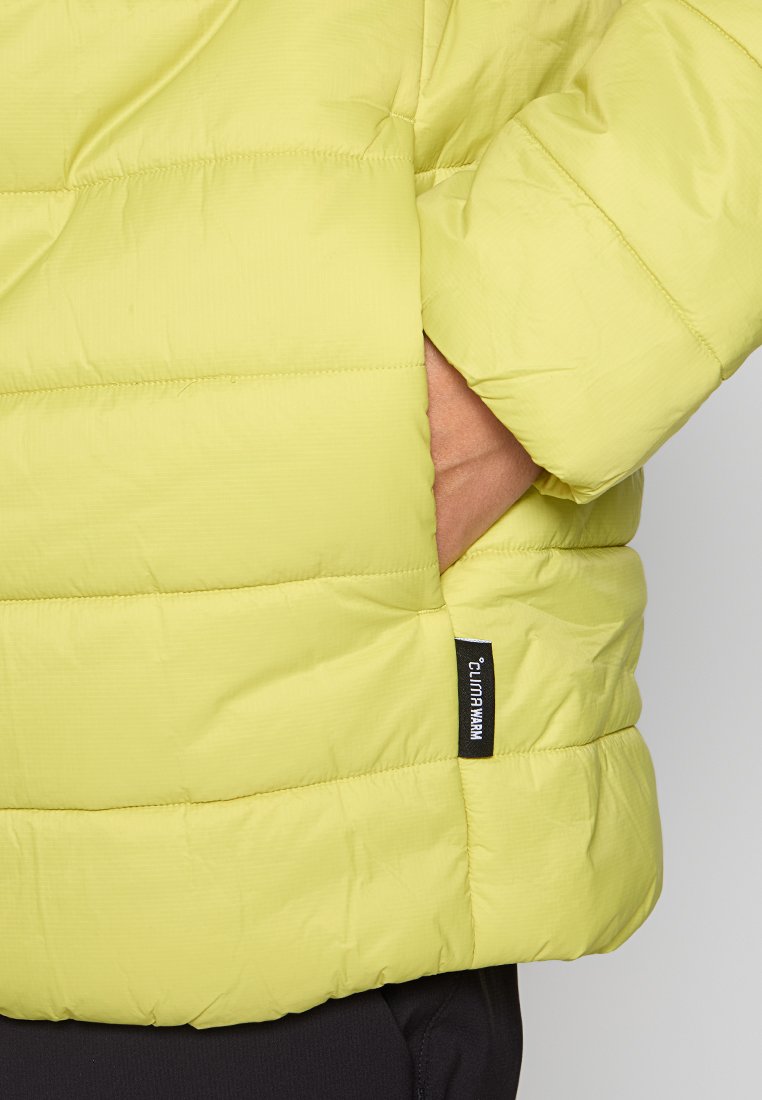 Chaqueta acolchada verde lima con textura acolchada, que presenta un bolsillo lateral y una etiqueta de marca en la manga. Material suave y ligero.