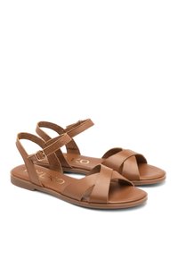 Brązowe skórzane sandały z płaską podeszwą, z krzyżującymi się paskami z przodu i regulowanym paskiem wokół kostki z metalową klamrą.