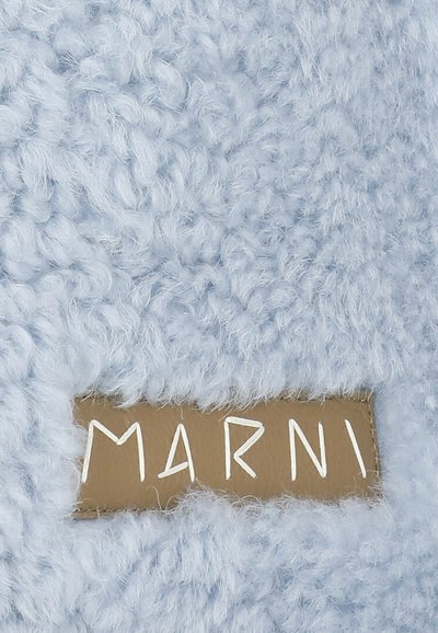 Tessuto azzurro chiaro e soffice con una superficie testurizzata e un'etichetta beige con la scritta "MARMI" in caratteri bianchi.