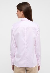 Helles rosa Langarmhemd mit Rückenpasse, geknöpften Manschetten und taillierter Passform. Aus glattem, leichtem Stoff gefertigt.