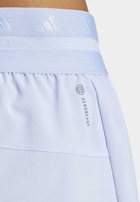 Light blue athletic shorts featuring a textured elastic waistband. The shorts have a visible "AEROREADY" logo and smooth fabric with pleats.