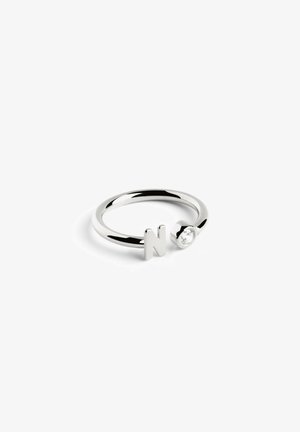 Anillo de plata con banda circular, adornado con la letra "N" y un pequeño acento de gema clara. Acabado liso y pulido.