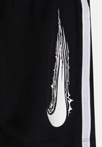 Pantalones cortos deportivos negros con un logo de Nike blanco, con acentos dentados. Incluyen rayas laterales blancas y una tela texturizada.