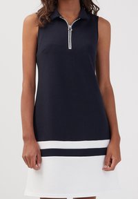 Robe polo sans manches en bleu marine, avec un col zippé, un ourlet blanc orné de rayures bleues marines, confectionnée dans un tissu lisse et texturé.