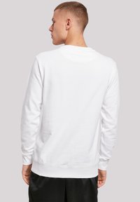 Hvit bomullsgenser med lange ermer, rund hals og ribbede mansjetter og nederkant. Glatt tekstur; minimalistisk design, ingen synlige grafikker.