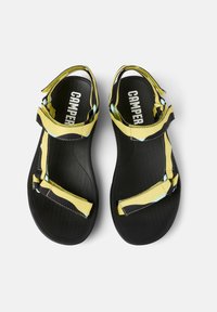 Black sandals with yellow and blue fabric straps, rubber sole, adjustable buckles, and textured footbed featuring the "CAMPER" logo.