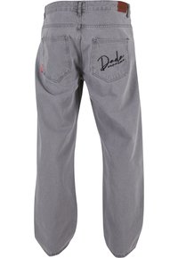 Gray denim jeans with a loose fit, featuring a leather patch at the waist and "Dada" embroidered on the right back pocket.