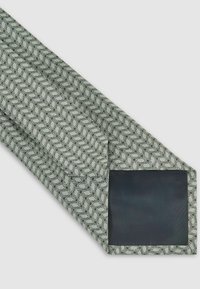 Lichtgroene stropdas met een geometrisch patroon in het zwart. Heeft een effen zwarte stofsectie aan de punt. Soepele textuur. Klassiek ontwerp.