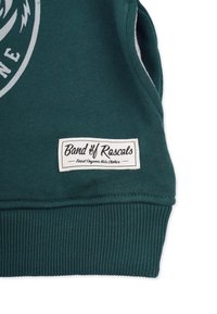 Grön sweatshirt med ribbad position och nederkant, som har en vit etikett med texten "Band of Rascals" i svart och en logotyp på framsidan.