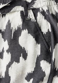 Mönstrad tyg med en svart och vit abstrakt design. Mjuk textur med en något grov väv. Metallmärke fäst.
