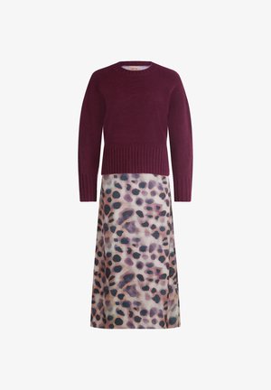 Bordeaux striktrøje med ribbet kant, parret med en lang, flodlignende nederdel med et pastelfarvet leopardmønster i nuancer af lilla og sort.