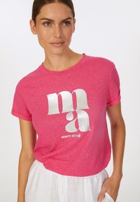 Pink cotton t-shirt featuring a shiny silver printed logo "mmaa" on the front; short sleeves and a relaxed fit with a soft texture.