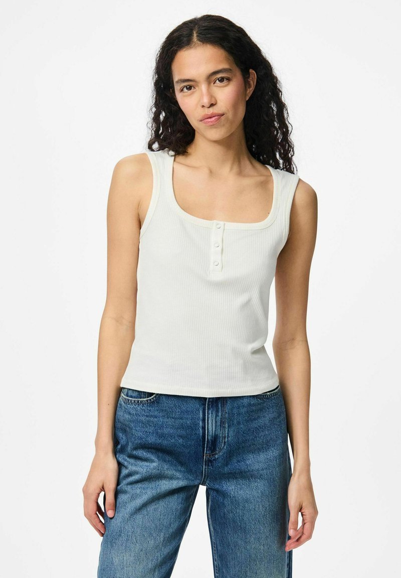 Top a righe bianco con scollatura quadrata e chiusura a tre bottoni sul davanti, abbinato a jeans in denim blu.
