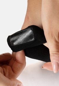 Calzino nero con un pannello a trama liscia e chiusura regolabile, mentre viene indossato su un piede con le dita che lo afferrano.