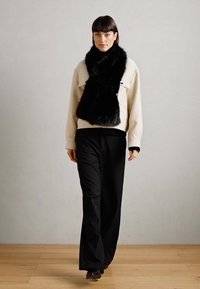 Cream sweatshirt with a black faux fur scarf, paired with black wide-leg trousers. Smooth texture, minimal design, and neutral color palette.