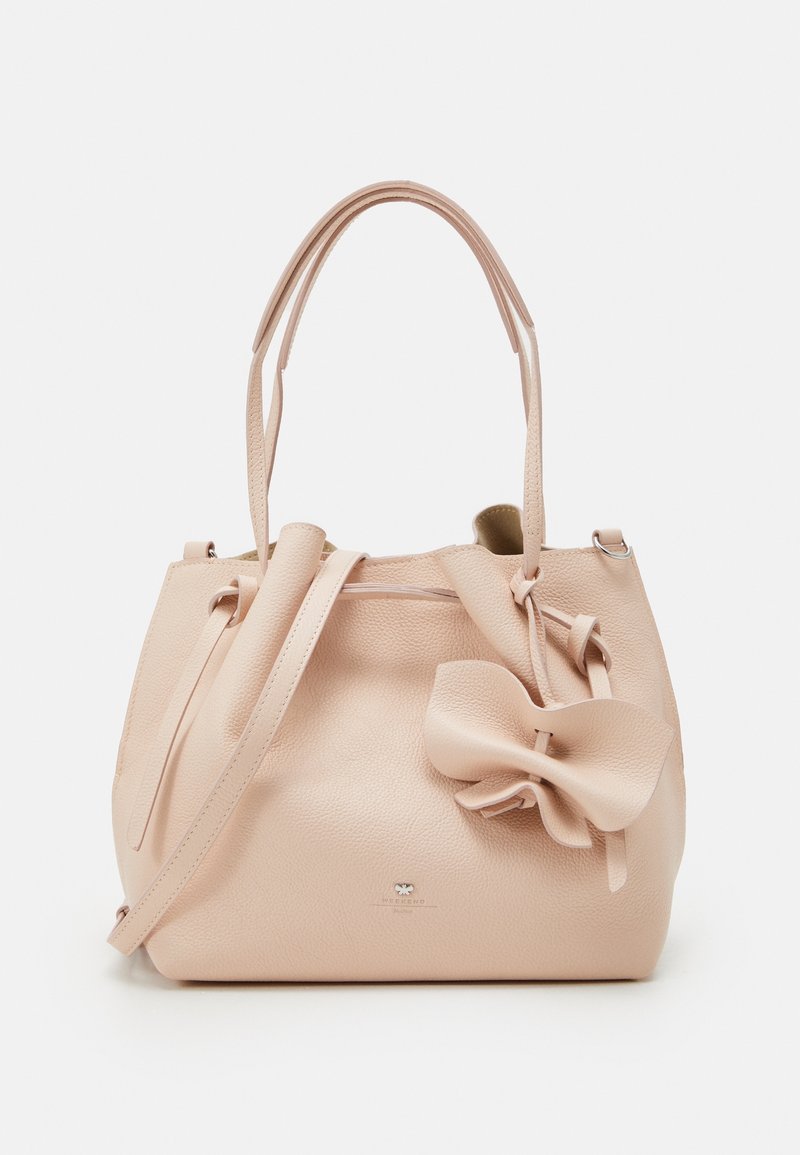 Sac à main en cuir beige avec deux bandoulières, un grand nœud décoratif sur le devant et un petit logo métallique de la marque près de la base.