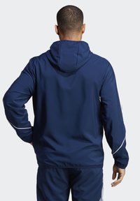 Donkerblauwe hoodie van lichte stof met elastische manchetten en tailleband, met witte accenten langs de mouwen en de capuchon.