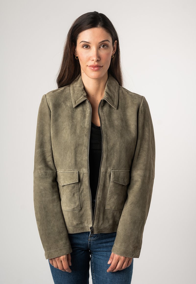 Giacca in suede verde oliva con colletto, chiusura frontale con zip e due tasche applicate. Presenta una texture liscia e un design semplice e pulito.