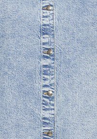 Lichtblauwe denimhemd met zilveren drukknoopjes, textuurstof en verticale stiksels langs de middenvoor.