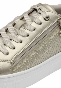 Sneaker in metallo dorato con pannello laterale testurizzato, lacci piatti e suola in gomma bianca. Presenta dettagli del logo sul lato e sugli occhielli.