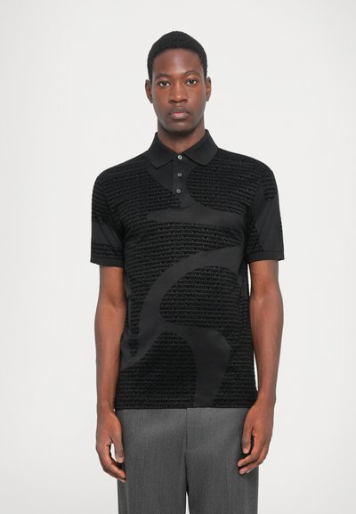 Fekete póló, melyen az "Emporio Armani" logó textúrált mintázata látható, klasszikus gallérral és rövid ujjakkal.