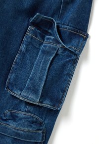Los pantalones cargo de mezclilla presentan un color azul profundo, múltiples bolsillos, costuras reforzadas y una tela texturizada para mayor durabilidad.