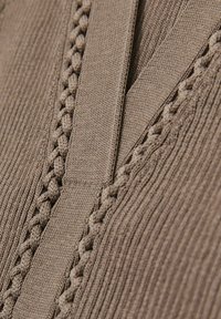 Tessuto lavorato a maglia marrone con texture a coste e un accento intrecciato. Il design presenta un scollo a V con cuciture verticali.