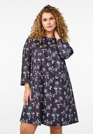 Vestido de estampado floral en azul marino oscuro con mangas largas, dos bolsillos frontales y un corte holgado. Presenta delicados acentos en verde menta y color óxido.
