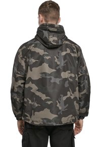 Vízálló, kapucnis álcázó kabát, sötétzöld, szürke és bézs mintázattal. Rugalmas mandzsetták és hem az állítható illeszkedésért.